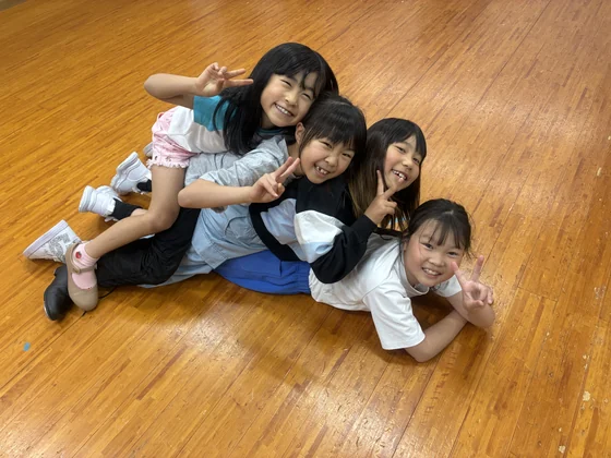 スタジオの床に座って笑顔を見せる子どもたち