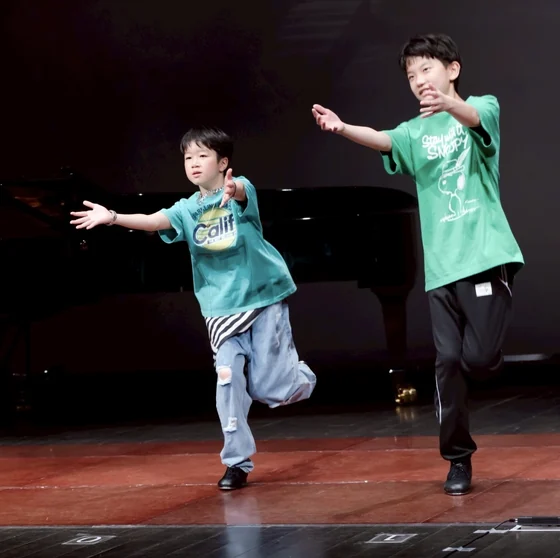 舞台で腕を広げて踊る二人