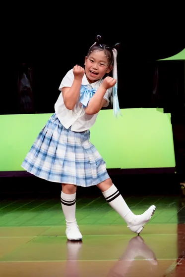 舞台で片足を上げて踊る子ども