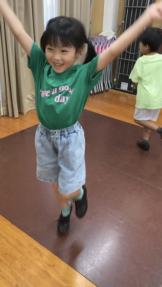 タップシューズを履いて腕を広げる子ども